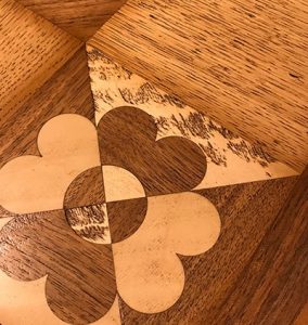 Dettaglio dell'intarsio: tavolo artigianale, legni pregiati, legno massello