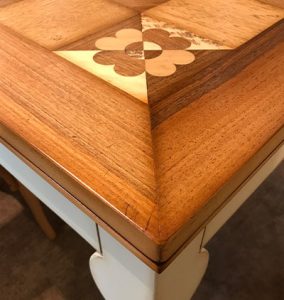 Particolare di tavolo artigianale intasiato con l'uso di legni pregiati e legno massello