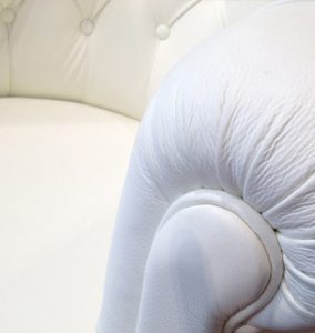 Particolare del bracciolo di poltrona capitonata in pelle colore bianco prodotta artigianalmente